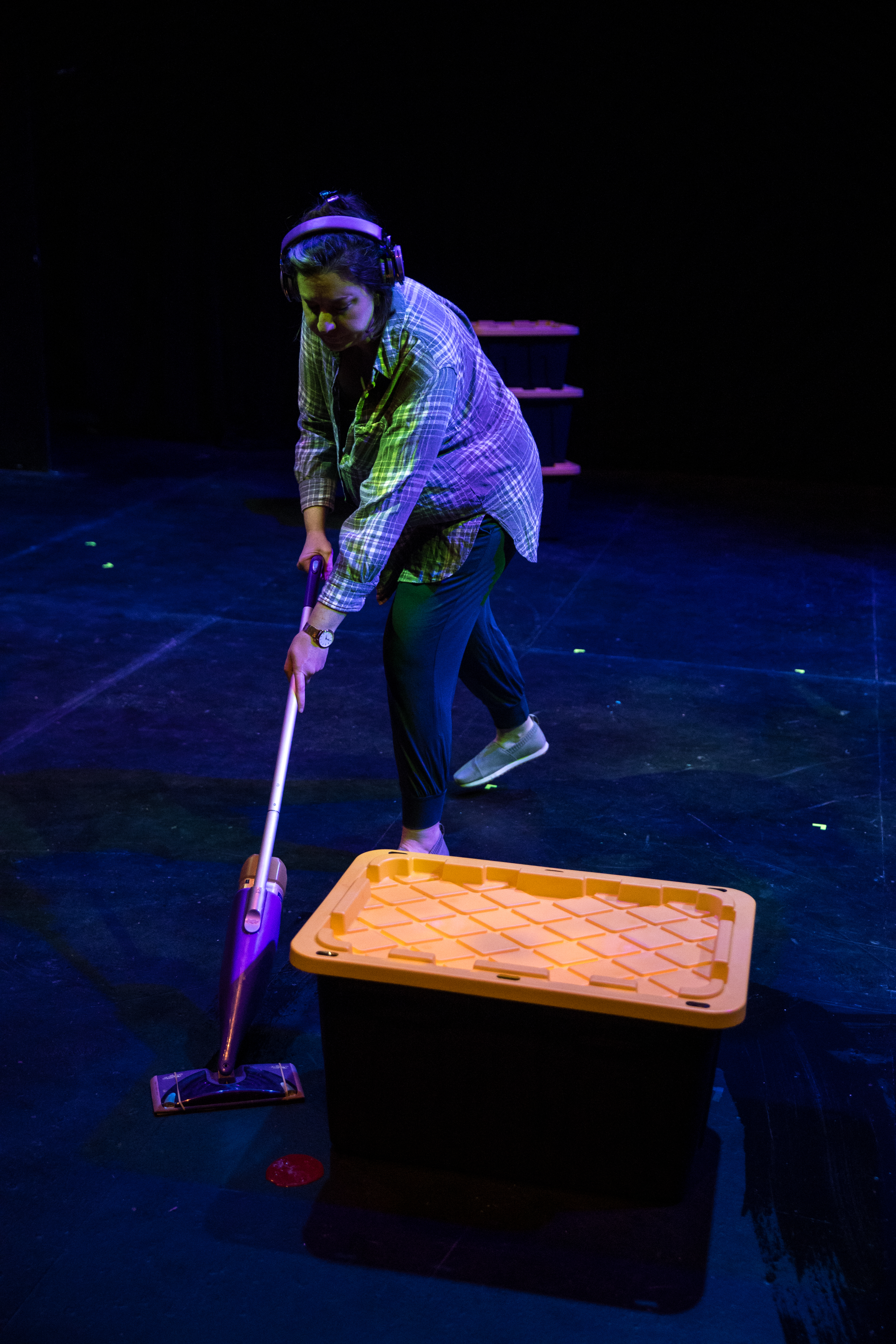 An actor onstage mops up a spot of blood by a bin